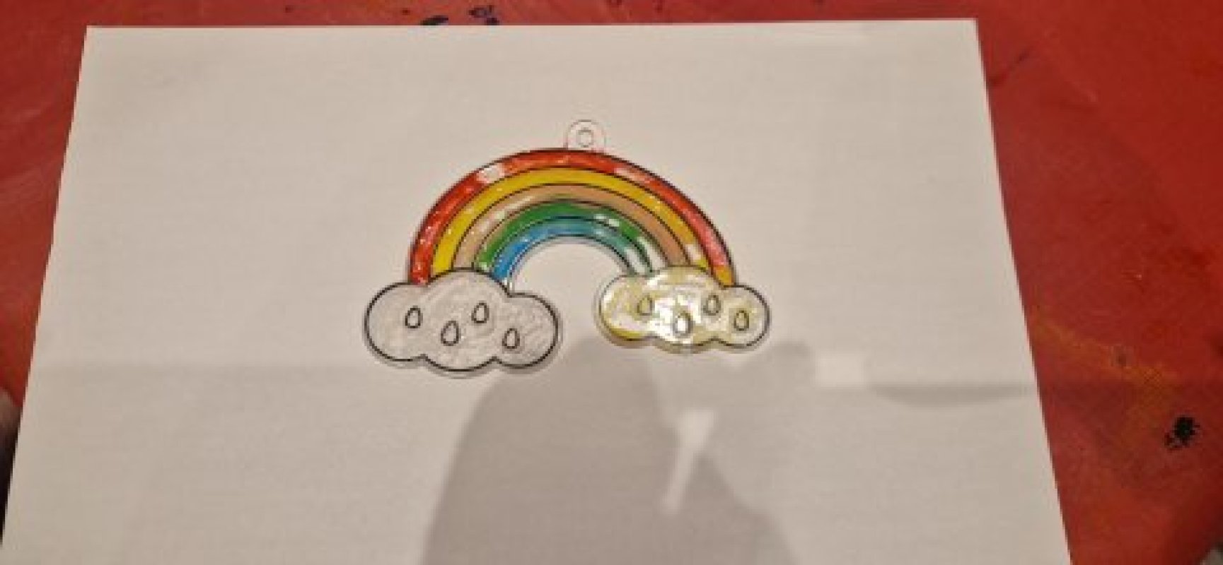 A colourful rainbow with two clouds other side and the colours are green blue yellow, and red.