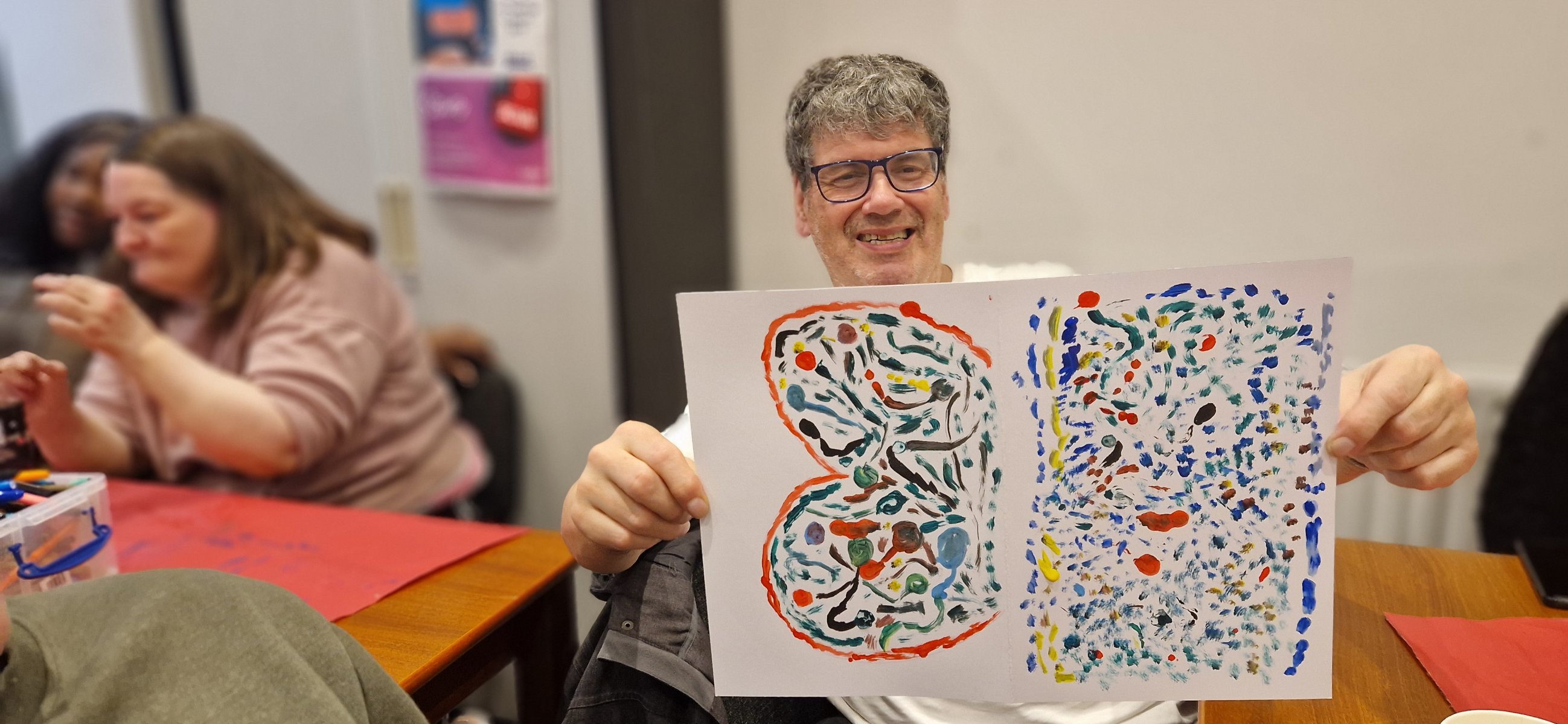 Smiling with glasses hog up two colourful abstract dotted paintings