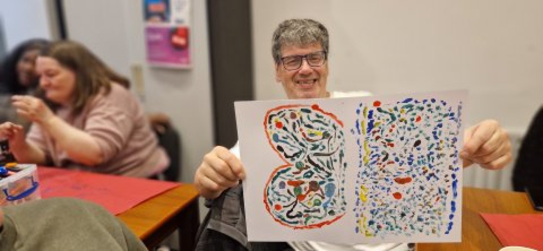 Smiling with glasses hog up two colourful abstract dotted paintings